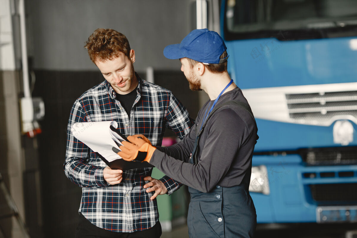 移动两个家伙在谈论工作在卡车附近的车库工作用货物转移文件白天年轻男性