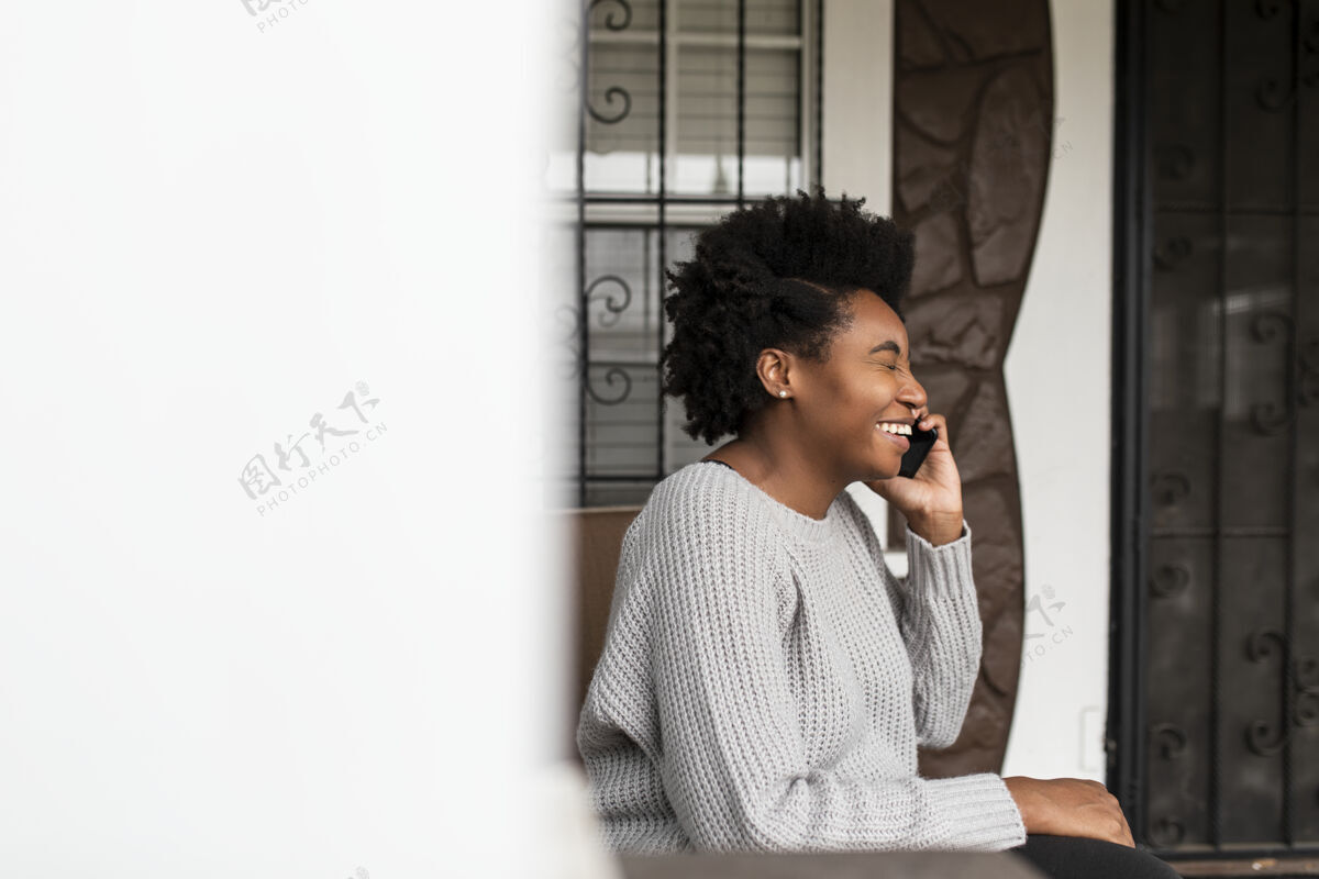 坐着非洲裔美国妇女在Covid19大流行期间打电话网络独自社会距离