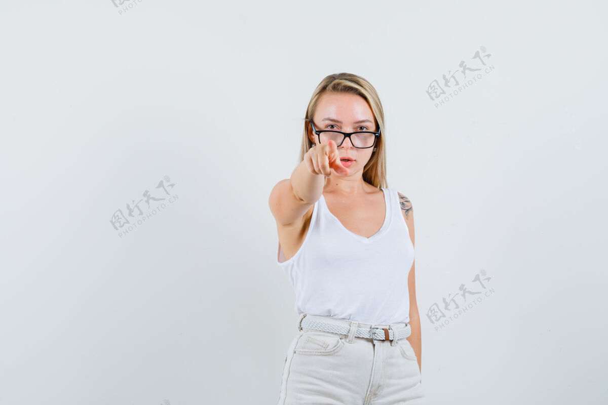 年轻金发女郎指着摄像机 穿着短裤 看起来很自信前视图皮肤单身肖像