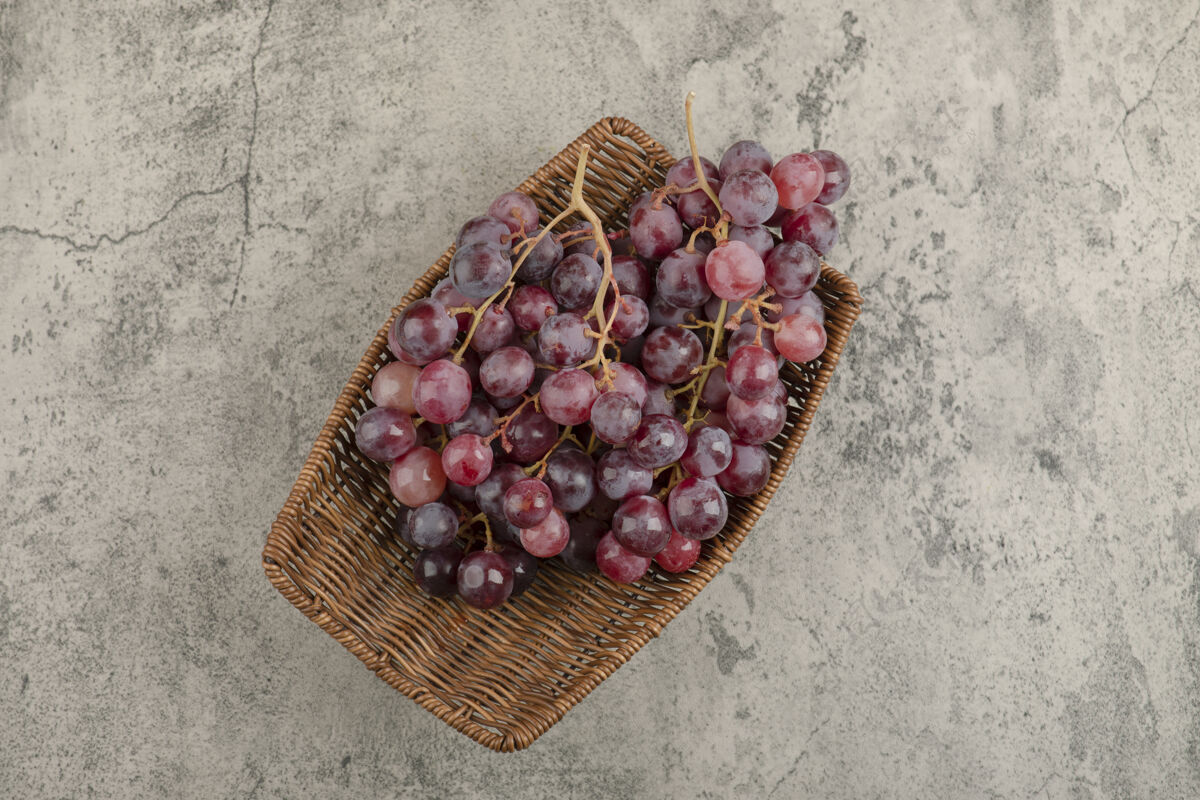 健康柳条篮美味的红葡萄放在大理石桌上自然食物顶视图