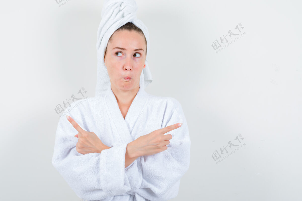 水疗穿着白色浴袍的年轻女士 手巾朝上 双臂交叉 神情犹豫不决 俯视前方年轻肖像健康