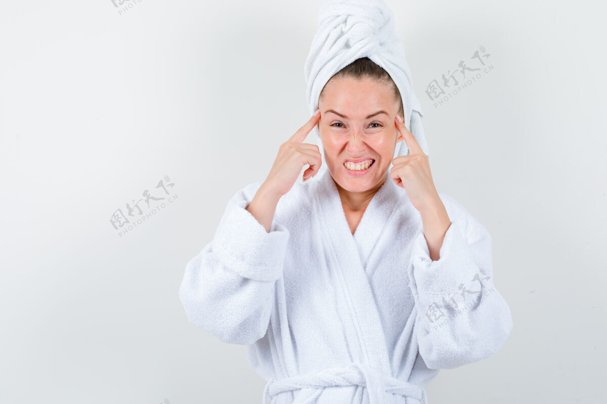 女孩年轻的女士拿着手指放在头上 穿着白色浴衣 毛巾 神情迷茫 俯视前方手指时尚成人