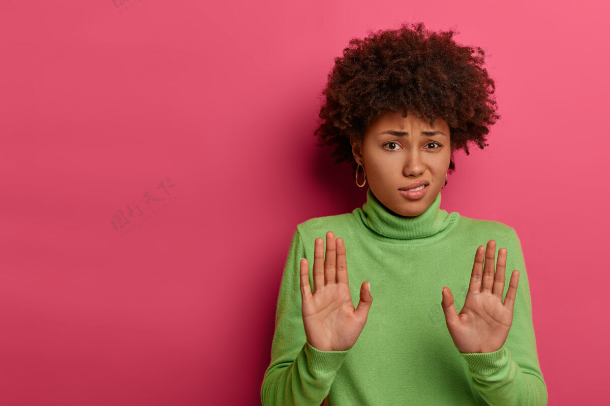防御一个非洲发型的笨拙无能的女人 向镜头拉着手掌 拒绝什么 拒绝求婚 穿着绿领毛衣禁止拒绝尴尬
