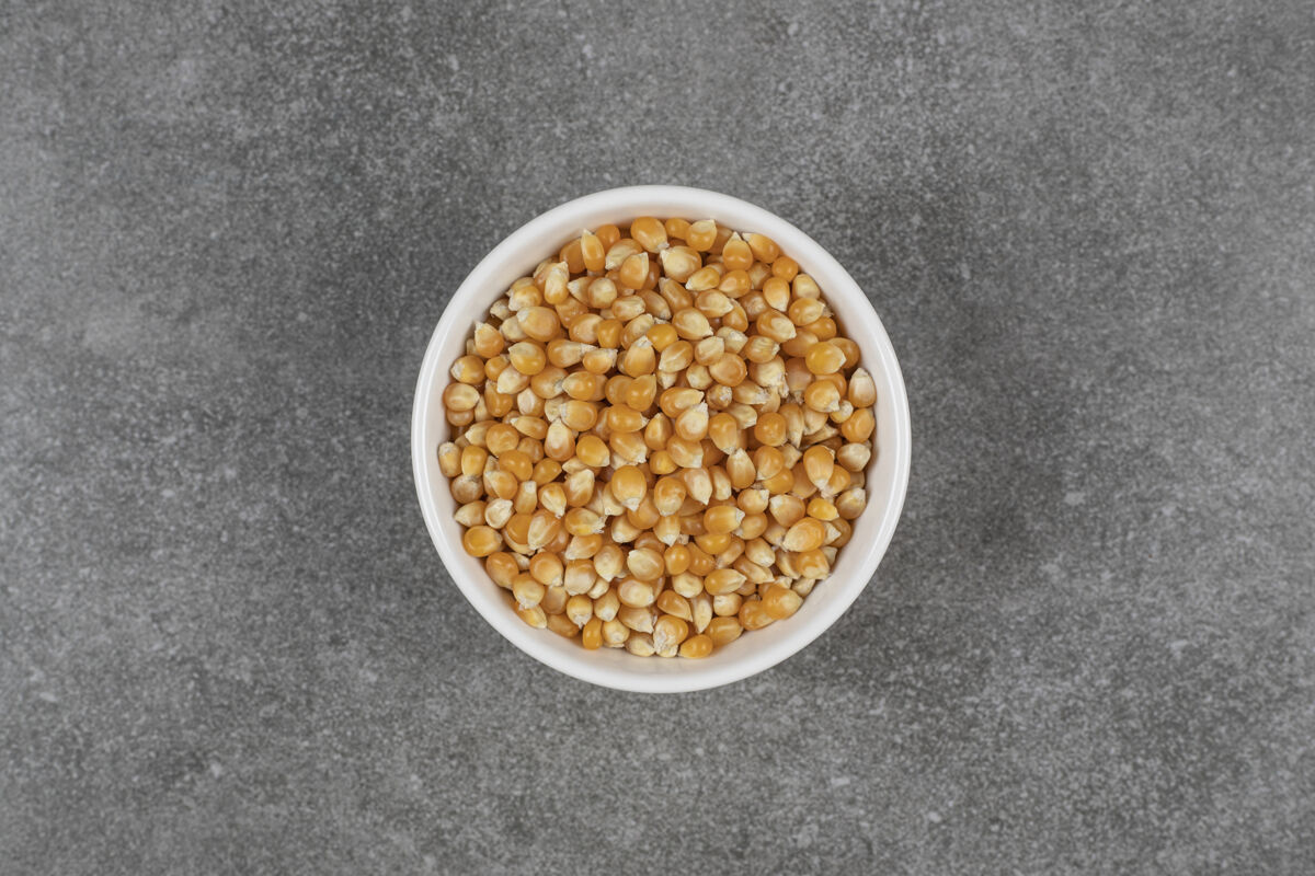 爆米花白碗里的一堆生玉米粒健康种子玉米
