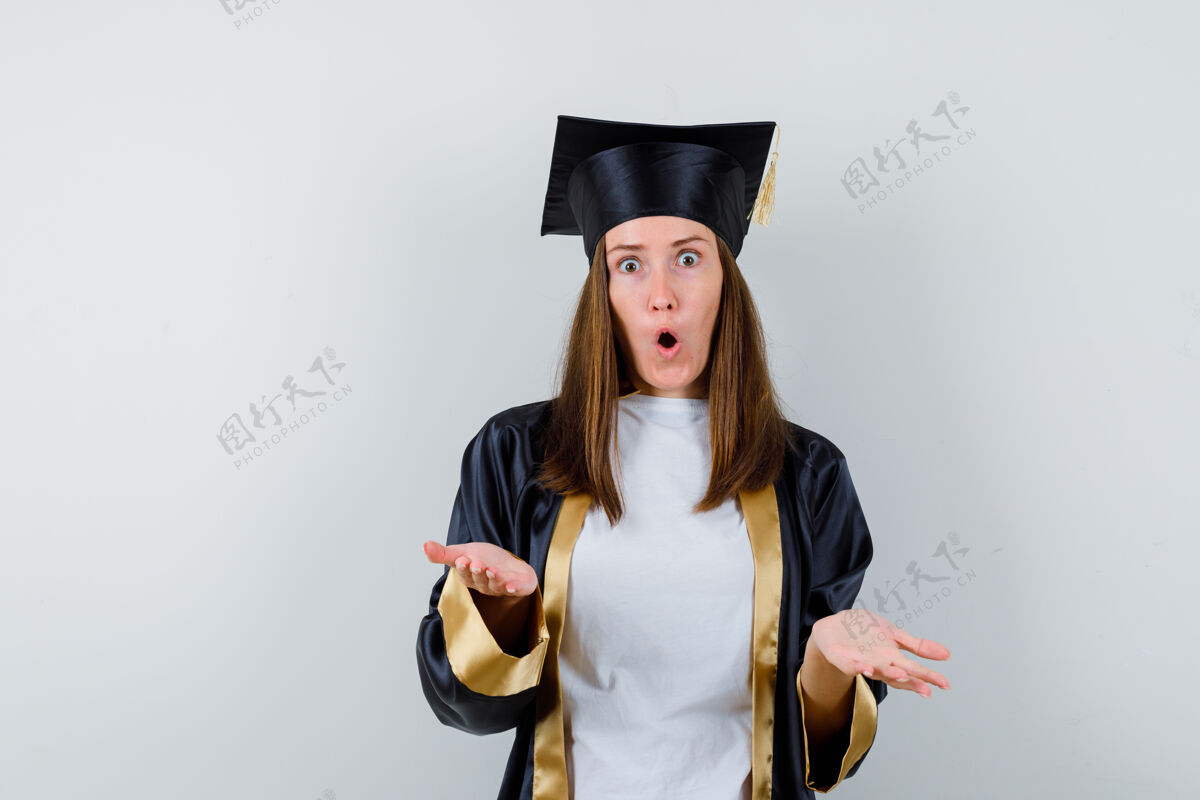 蔓延女毕业生摊开双手在镜头前困惑的姿势在制服 休闲服前视图衣服手学士