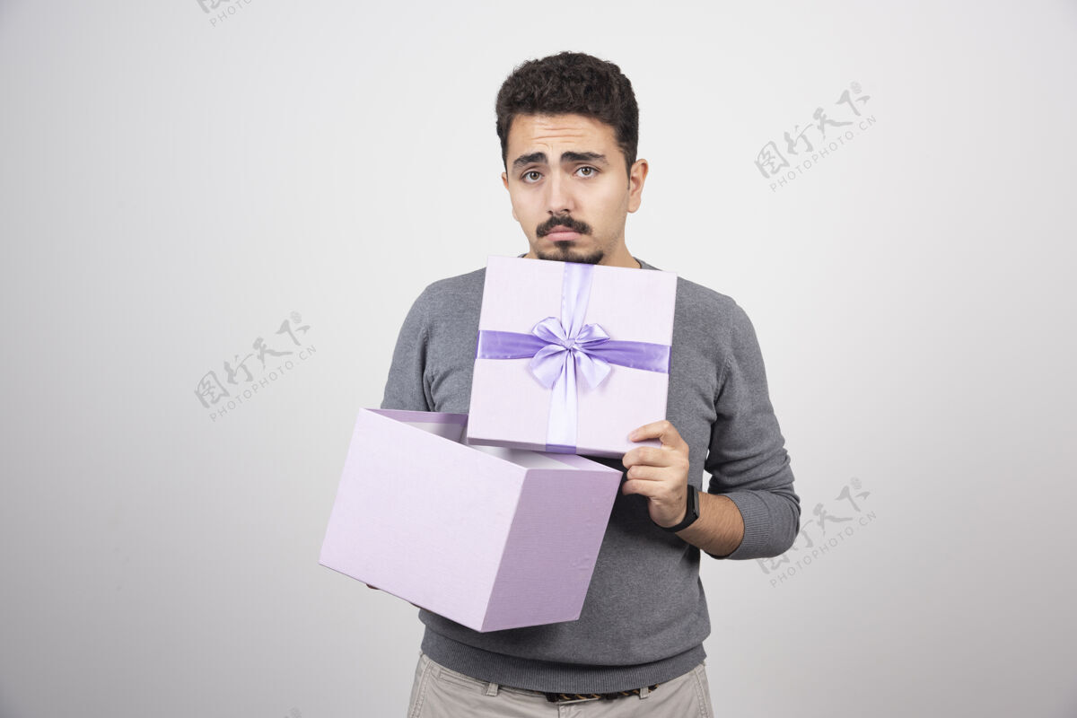 模特悲伤的人在白墙上打开一个紫色的盒子盒子人类礼物