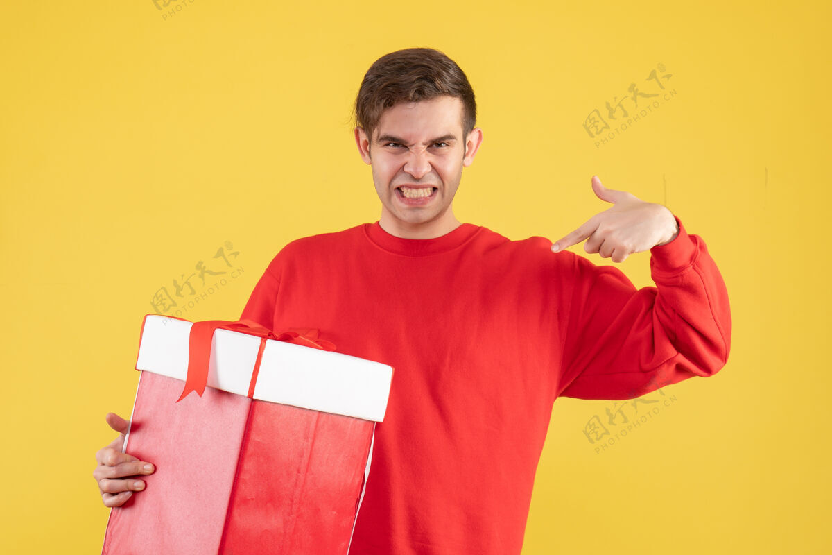 办公室正面图：穿着红色毛衣的年轻人指着黄色背景上的自己人视图前面