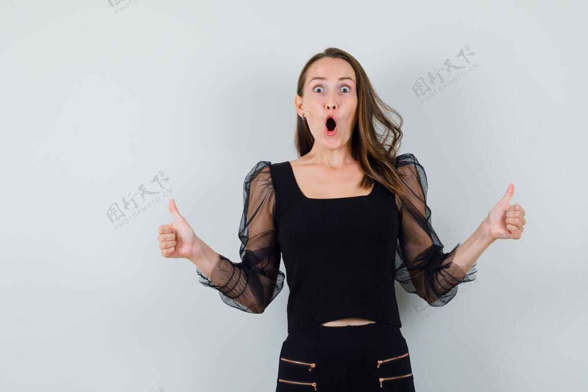 护理身穿黑色上衣和黑色裤子的年轻女子向上竖起大拇指 看上去很开心正视图双人女性衬衫