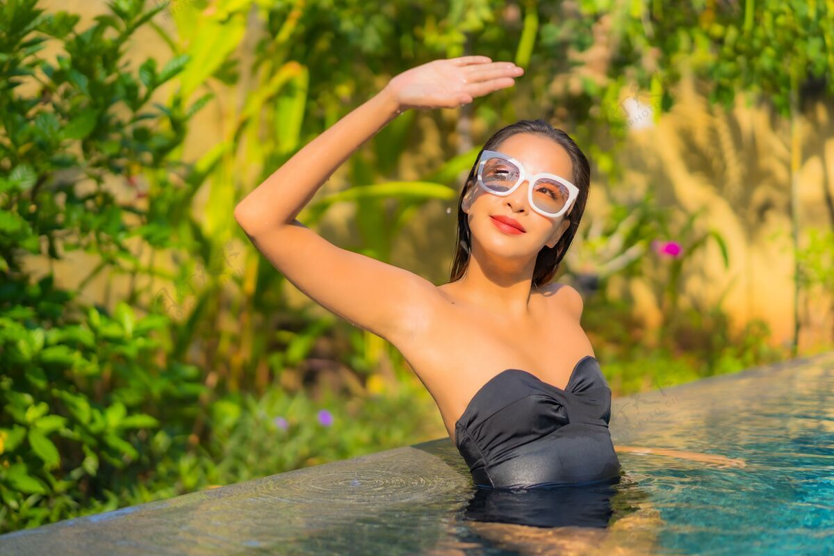 海滩美丽的亚洲年轻女子在游泳池里放松的画像奢华人健康