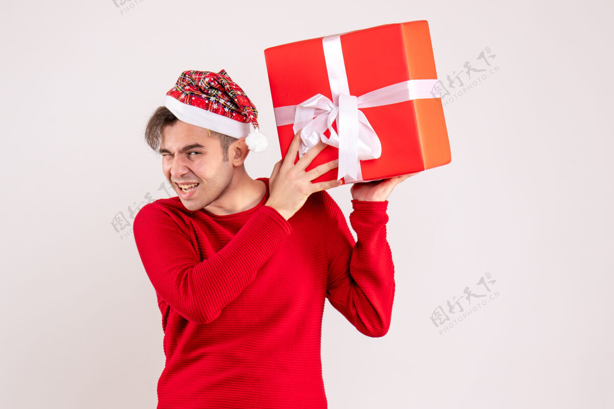 礼物正面图：戴着圣诞帽的年轻人拿着白色背景的礼物圣诞老人可爱微笑