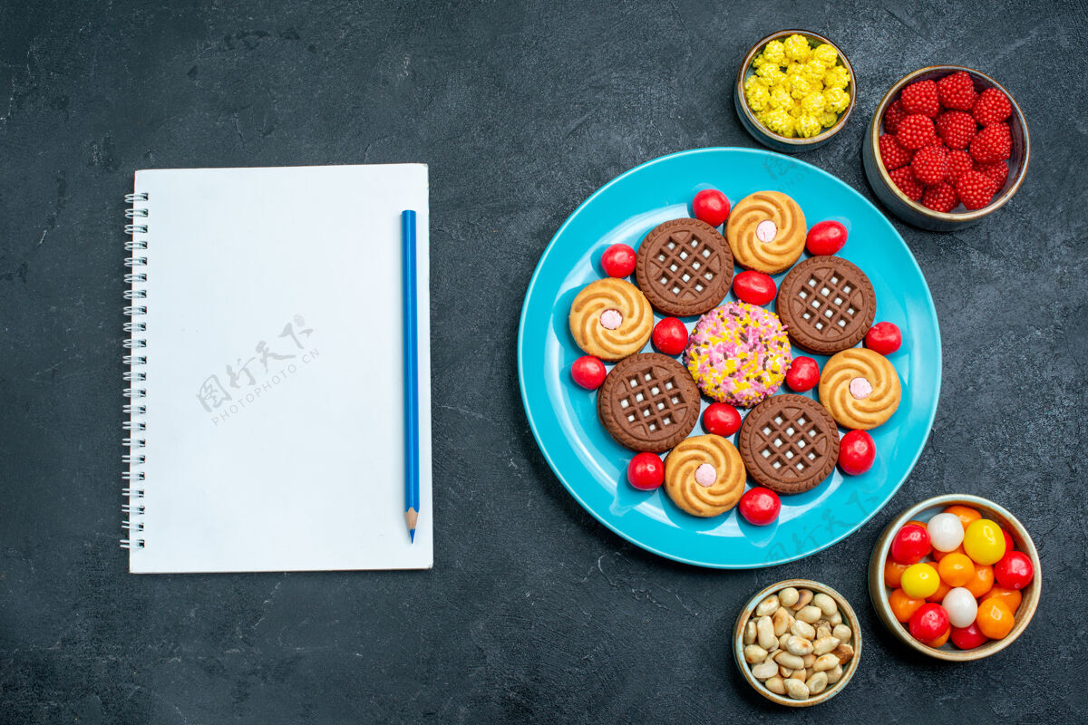 盘子顶视图不同的糖饼干与糖果在盘子里的灰色表面糖果甜饼饼干糖生的糖果饼干