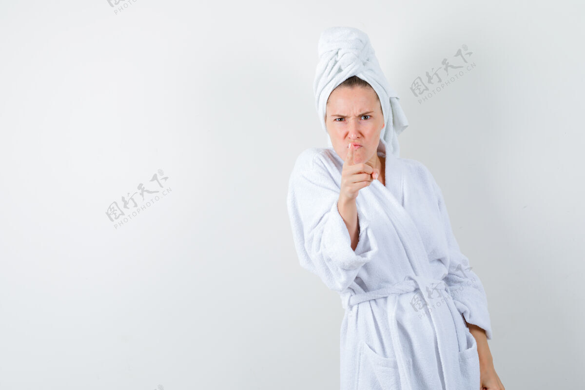 成人照片中的年轻女子穿着白色浴衣 毛巾指着摄像机 怒气冲冲地看着前方女性女孩时尚