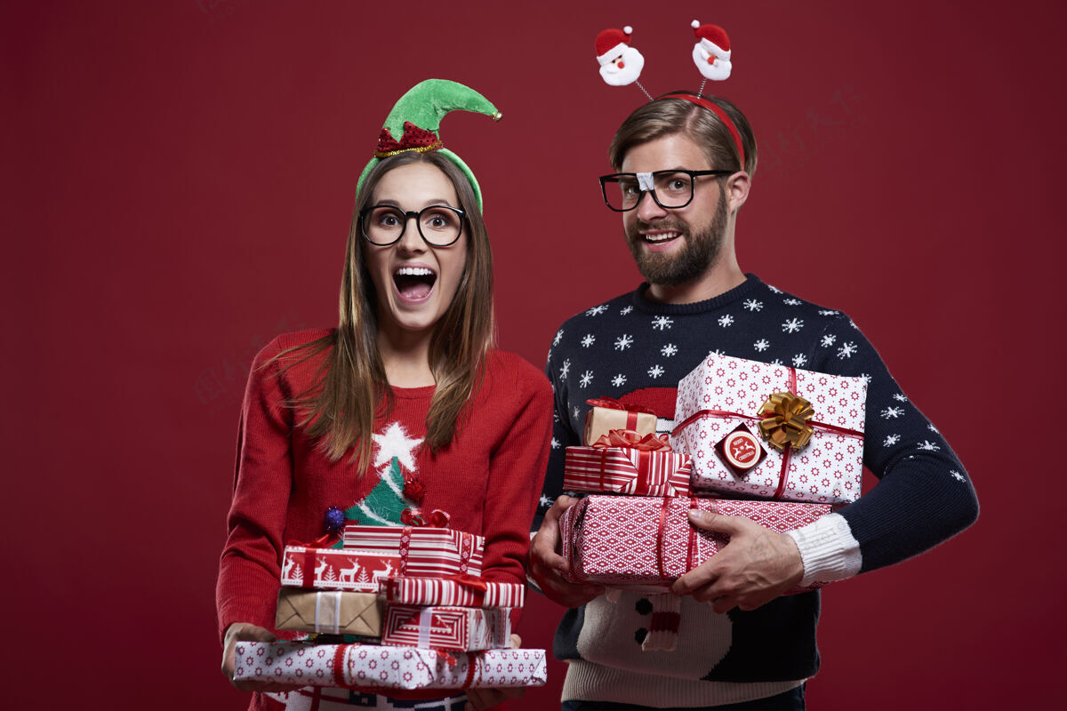 情侣一对圣诞夫妇拿着沉重的礼物盒子尖叫开衫