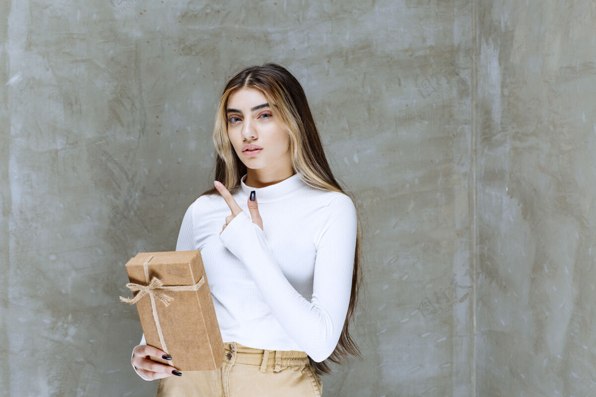 礼物一个女孩模型的图像 一个纸礼物指向石头上方一个人包装