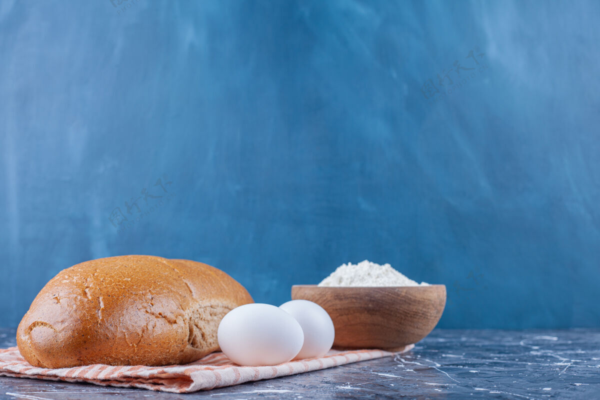 面粉一碗面粉 洗碗水和切片面包放在茶巾上 放在蓝色的桌子上烘焙美味美味
