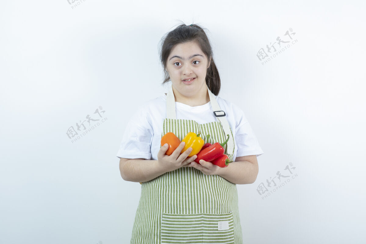 成人年轻漂亮的女孩站在格子围裙里 手里拿着蔬菜残疾年轻人姿势