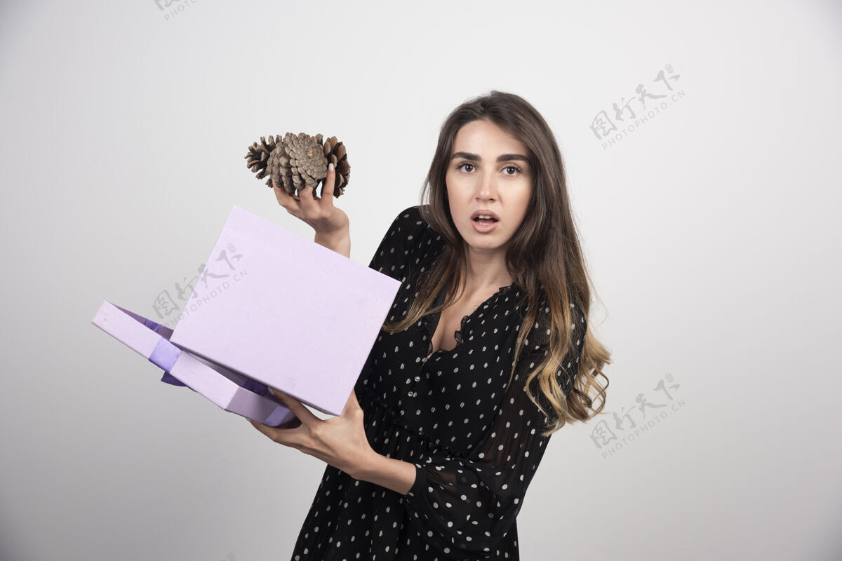 女孩一个拿着两个大松果的紫色盒子的年轻女人圆锥体站立松树