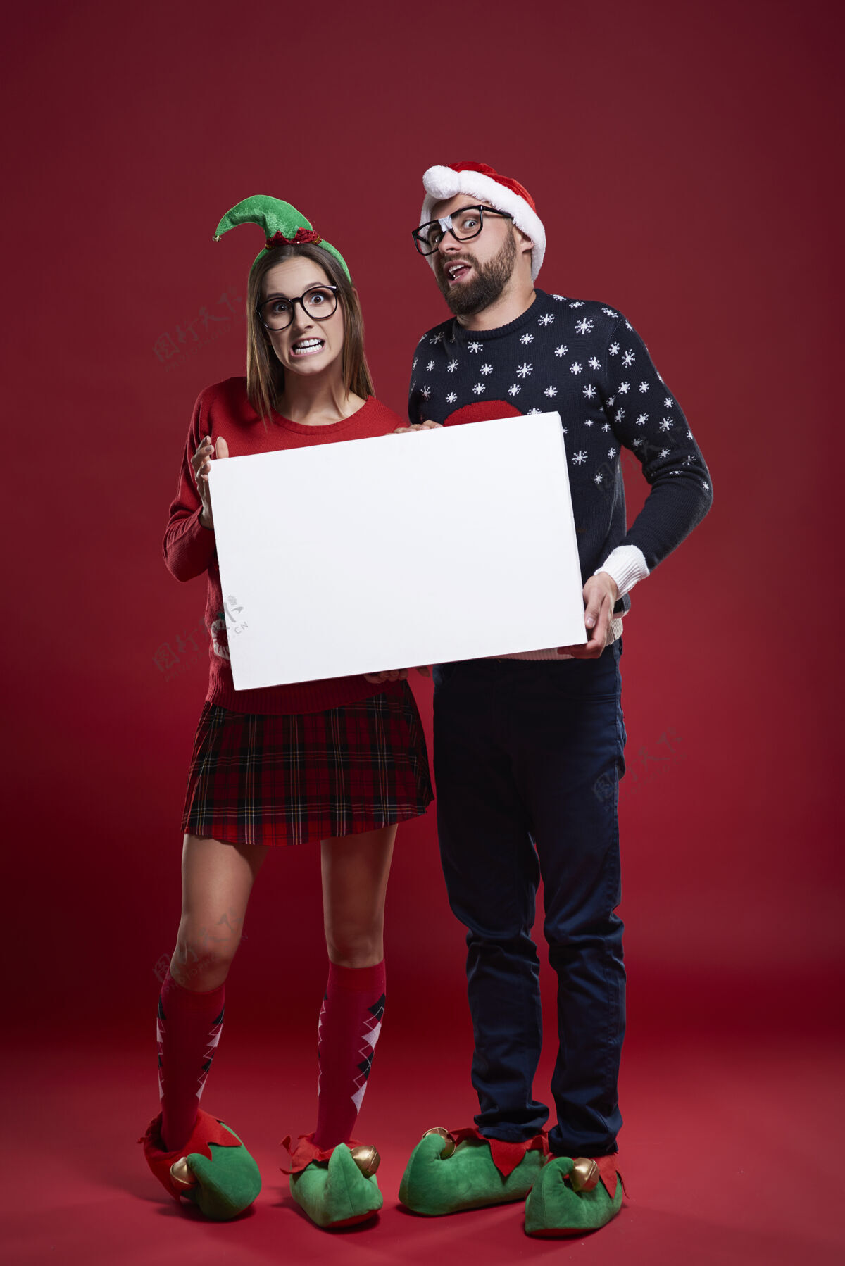 书呆子快乐的书呆子夫妇穿着圣诞服装拿着白纸怪人圣诞帽站起来
