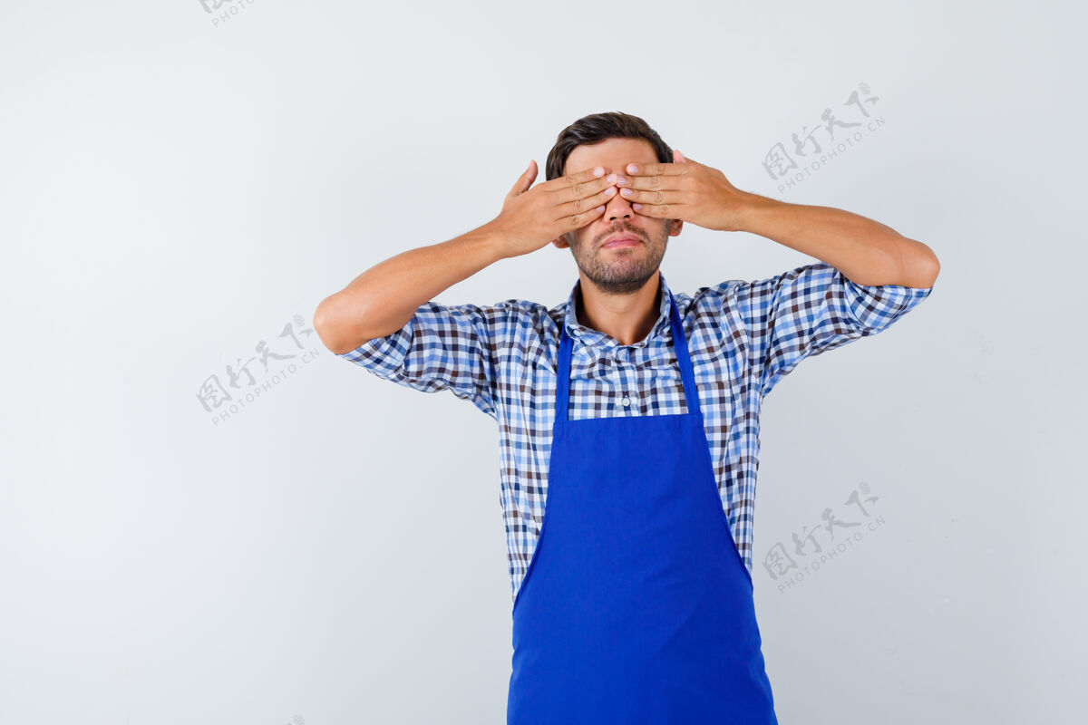 烹饪穿着蓝色围裙和衬衫的年轻男厨师制服男士男士
