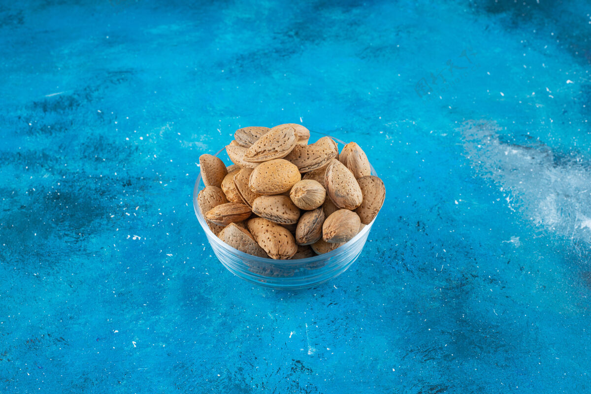营养蓝色表面上放着一碗带壳杏仁美味健康美味
