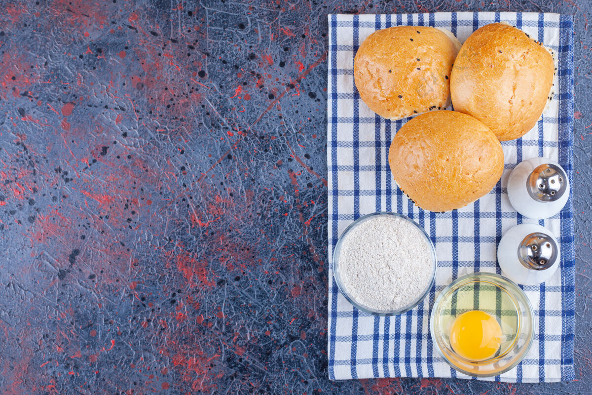 碗面包 一碗面粉和一碗鸡蛋放在茶巾上 放在蓝色的桌子上美味面粉美味