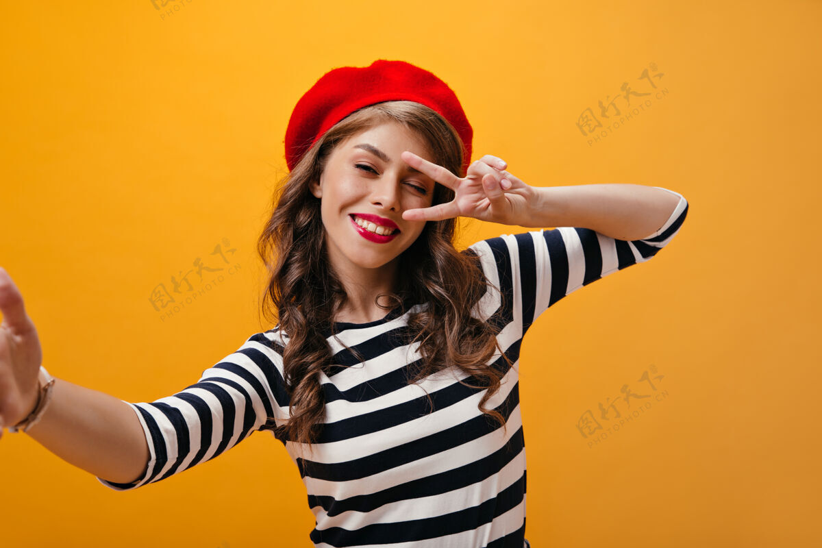 女人漂亮的女士在条纹衬衫上展示了和平的标志 让自己变成了一个快乐的女人女人 女孩 头发 空间 脸 橙色 微笑 衬衫 黄色 帽子 帽子 自拍 女性 紫色 年轻 表情 肖像 成人 一个 复制 条纹 休闲 姿势 牛仔裙
