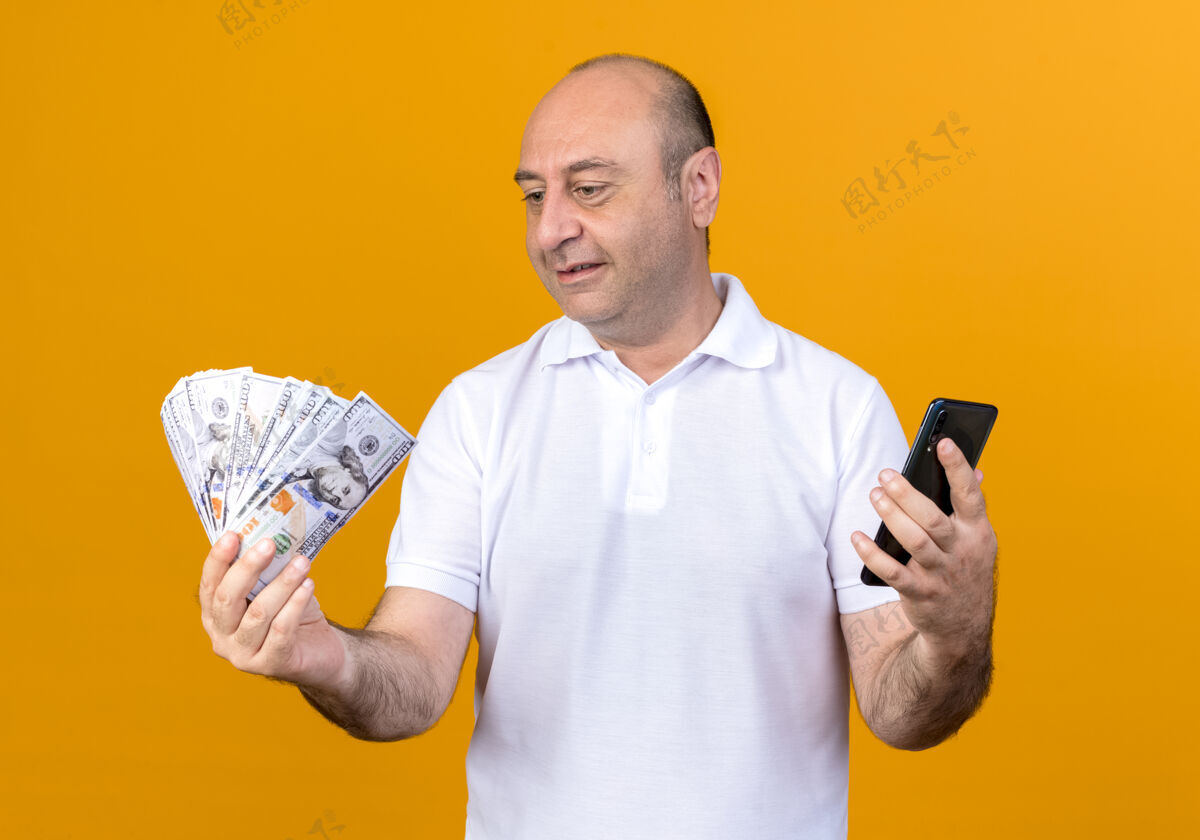请快乐随意的成熟男人拿着手机 看着手里的钱孤零零地放在黄色的背上钱成熟手