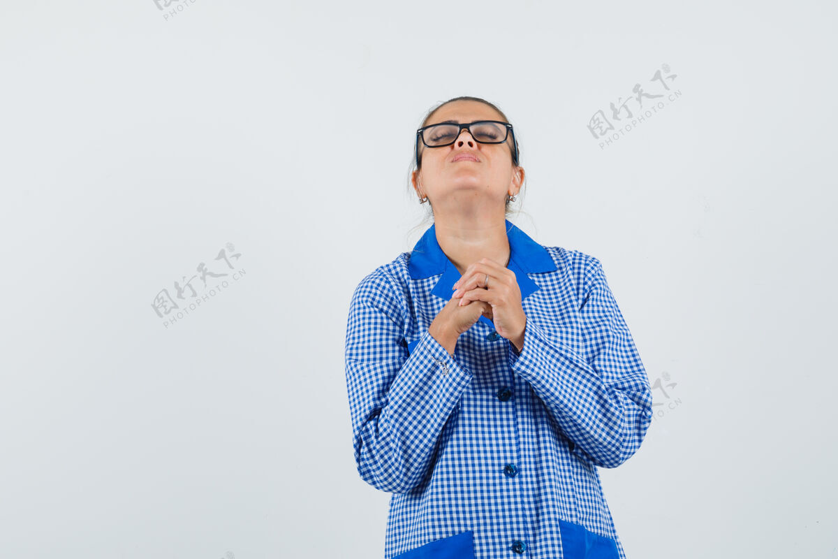 人年轻女子穿着蓝色方格布睡衣 戴着眼镜祈祷 目光集中正视图干净祈祷化妆品