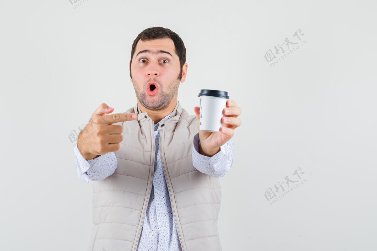 惊喜身穿米色夹克的年轻人用食指指着外卖咖啡杯 一脸惊讶 眼前一亮外卖帅哥夹克
