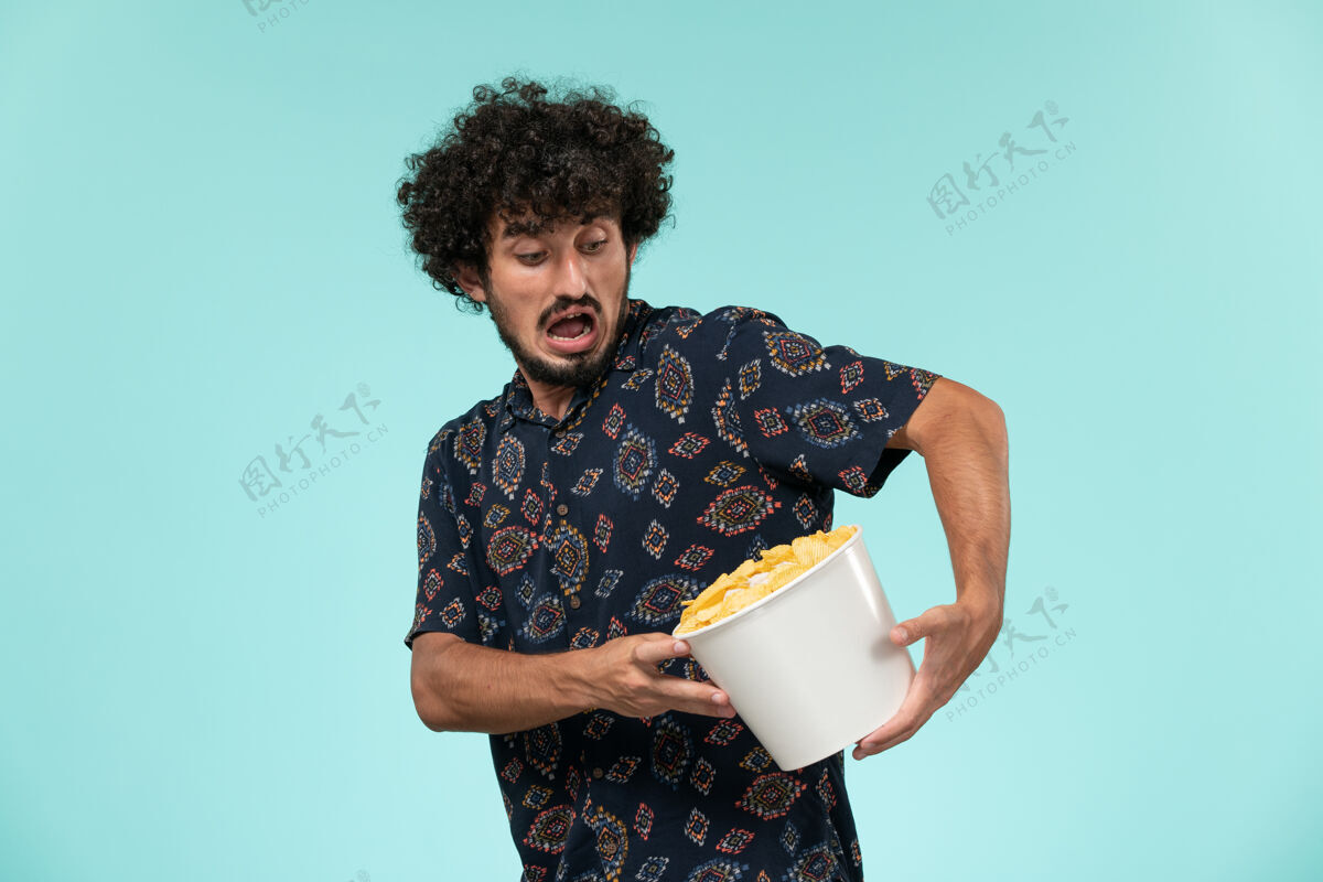 电影前视图年轻人拿着篮子和土豆cips在一个蓝色的墙遥远的电影院电影土豆电影院