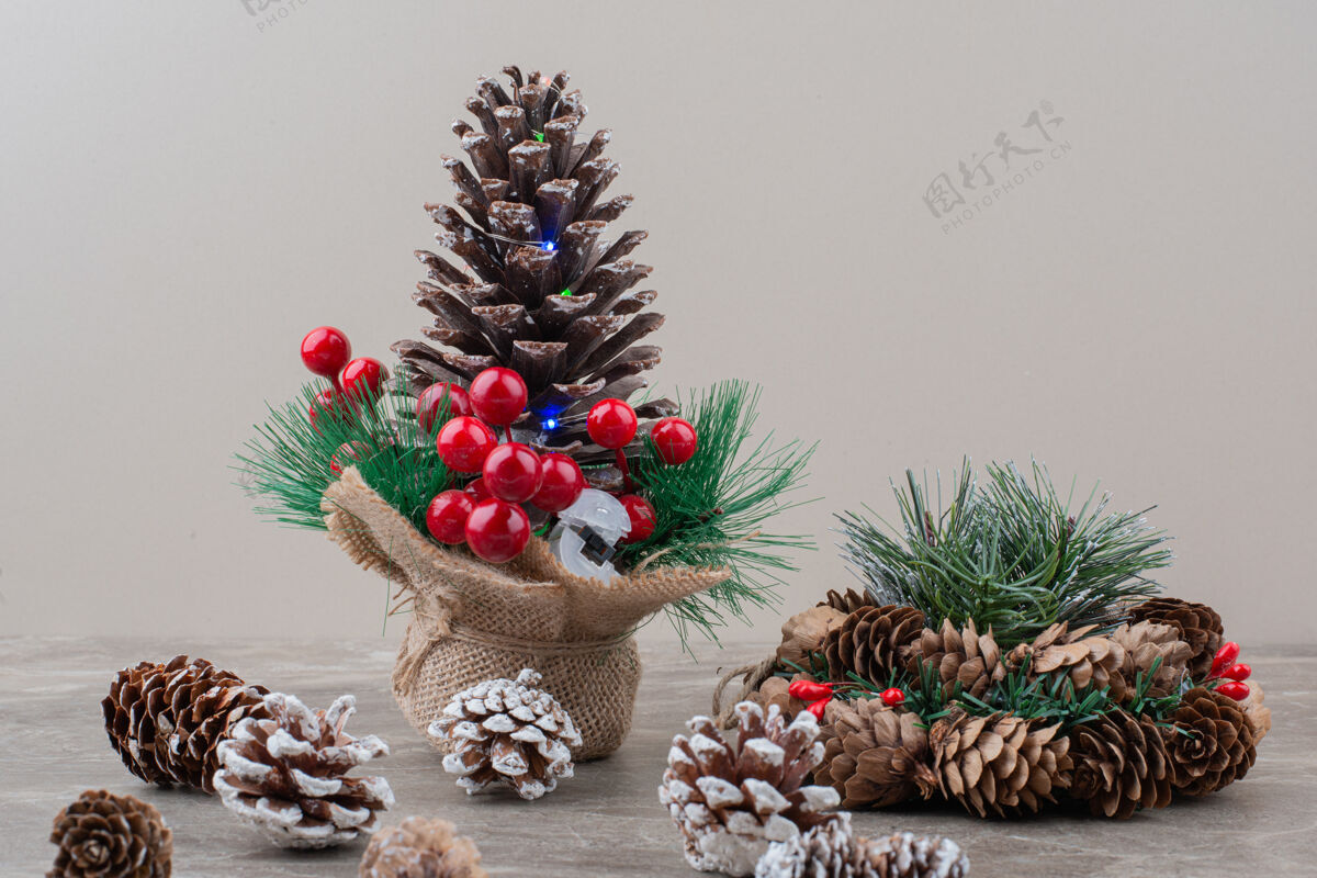 圣诞节用冬青浆果和树枝装饰的松果放在大理石桌上树枝冬天松树