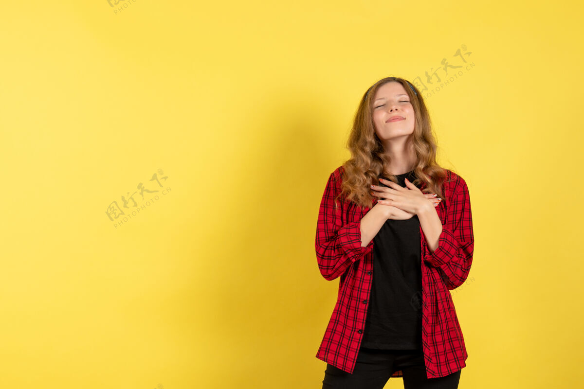 人正面图身着红色格子衬衫的年轻女性站在黄色背景上的女孩彩色模特人类女性衬衫格子肖像