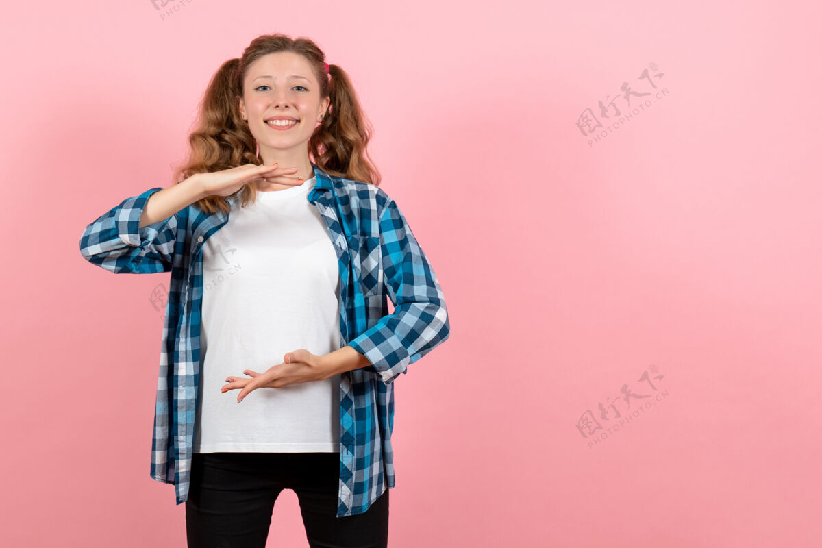 漂亮正面图身着蓝色格子衬衫的年轻女性在粉色背景上摆姿势 女性儿童青春色彩情感模型孩子格子微笑