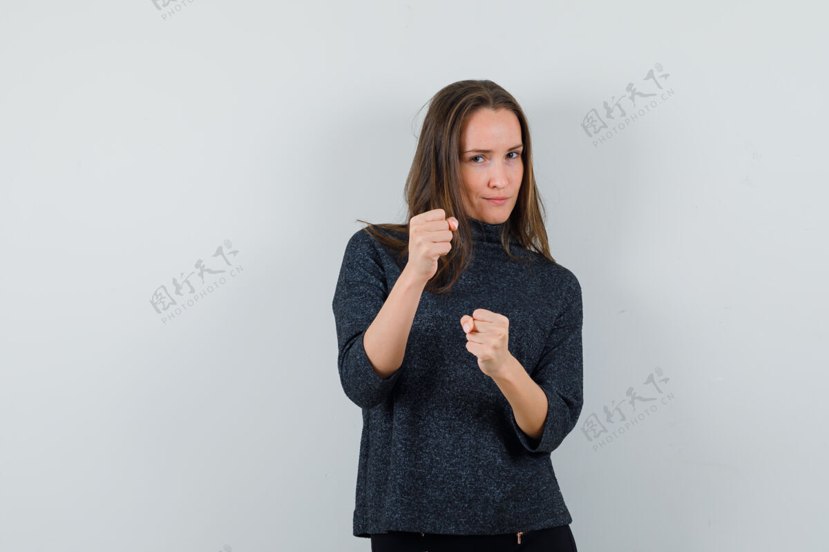 性感年轻女子站在一个拳击姿势在衬衫和看起来自信前视图自信手化妆