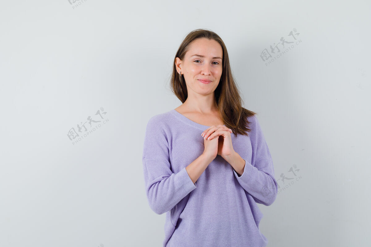 漂亮年轻女性双手放在胸前 穿着淡紫色上衣摆姿势 看起来很放松前视图优雅女性结合
