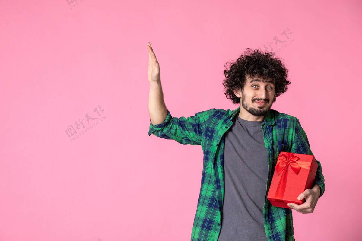 红色包装浅粉色墙上红色包裹的年轻男性正面图卷发衬衫包装
