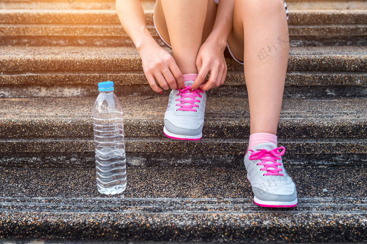 运动年轻女子跑步者系鞋带锻炼概念放松慢跑路