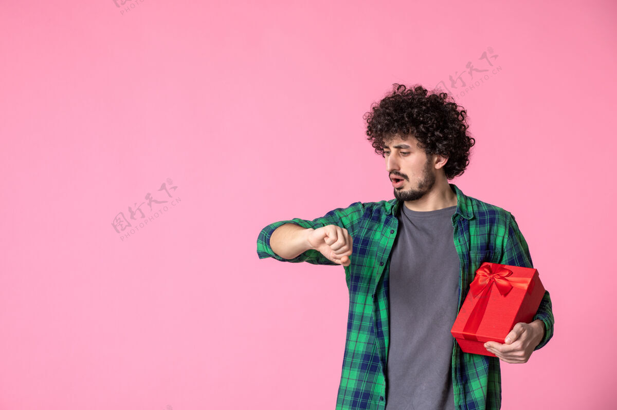 蝴蝶结浅粉色墙上红色包裹的年轻男性正面图人红色包装日期