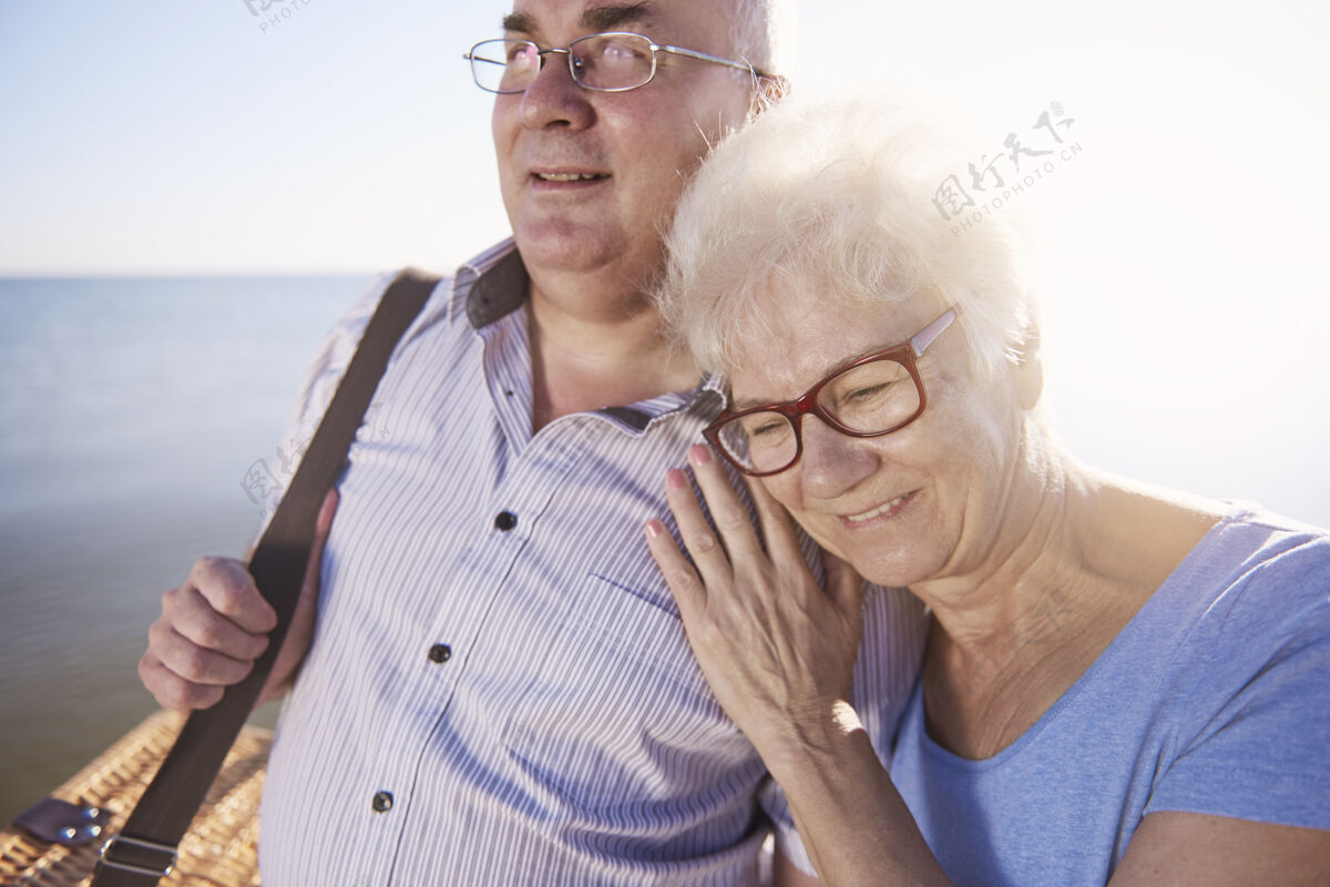祖父老人们在海滩野餐时拥抱着海洋人际关系欢乐