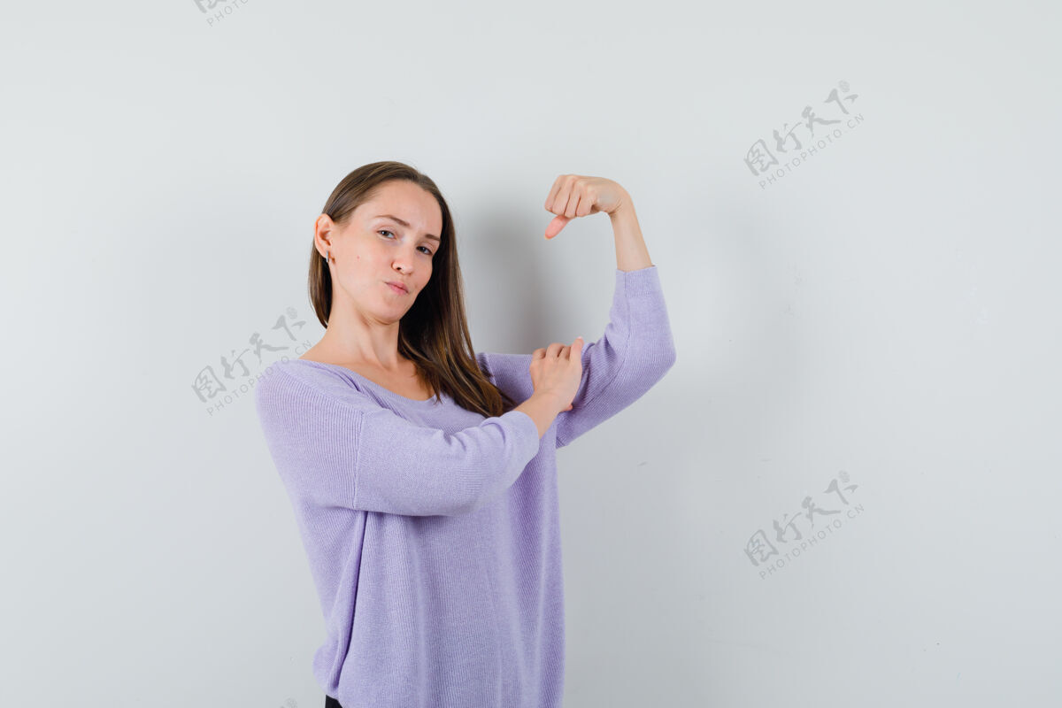 秀身穿淡紫色上衣的年轻女性 展示了她的手臂肌肉 看起来很有力量皮肤护理力量护理