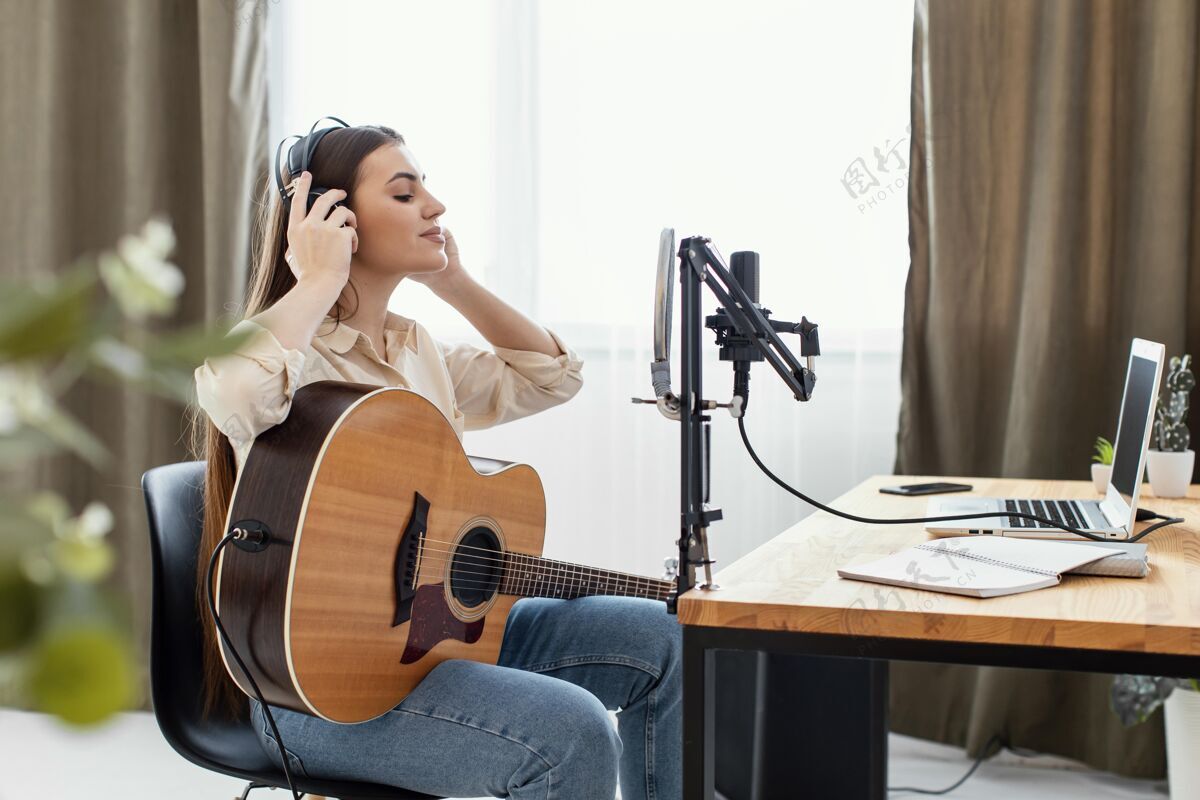 房子侧视图的女音乐家演奏原声吉他和准备录制歌曲在家里音乐家麦克风表演