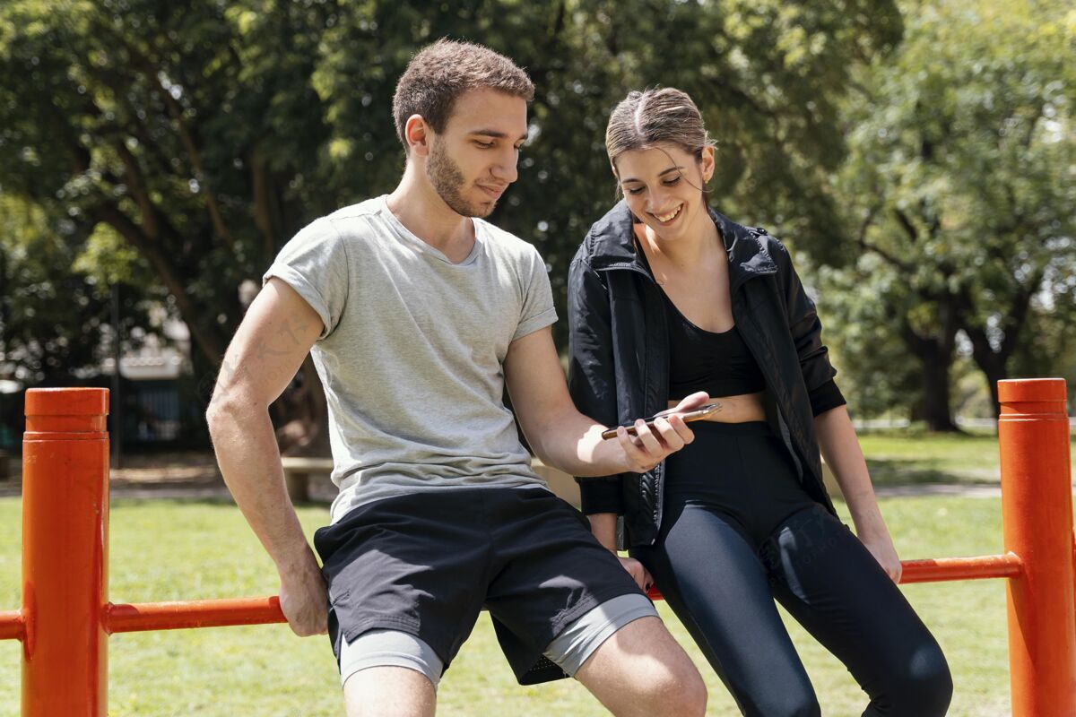 活泼户外运动时手持智能手机的男女正面图活力训练男人