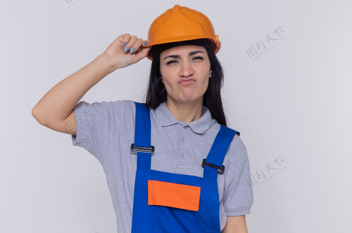 头盔年轻的建筑女工穿着建筑制服 戴着安全帽看着摄像机建筑建筑工人站着