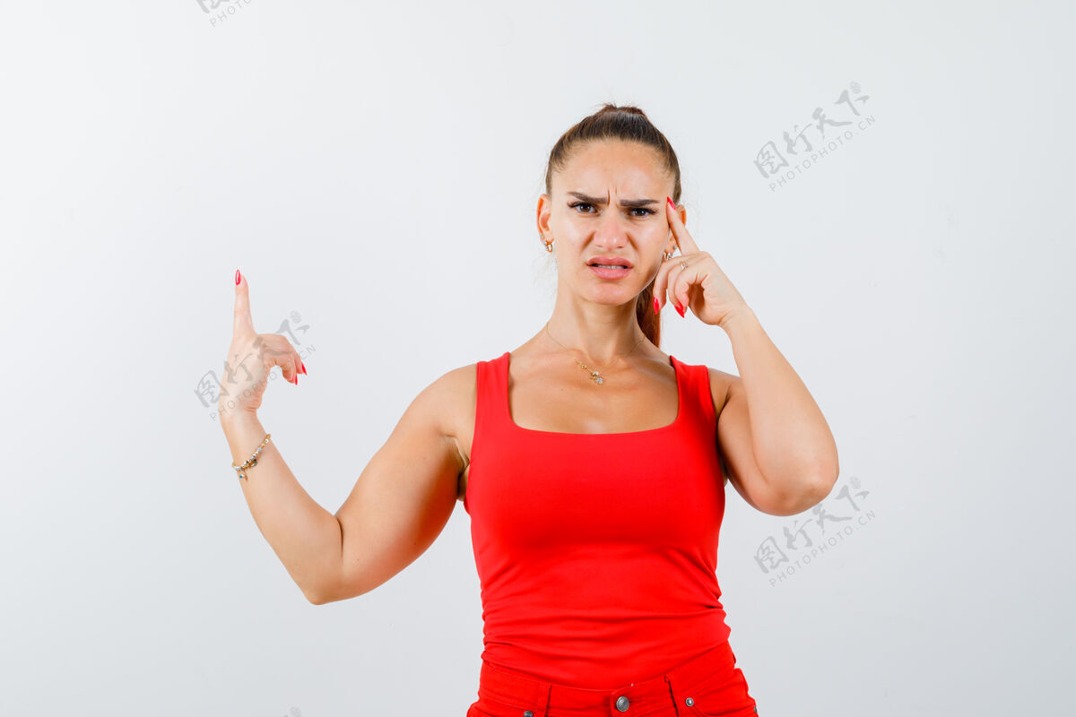 思想年轻的女性指着红色的背心 裤子 看着体贴前视图成人悲伤的情绪肖像