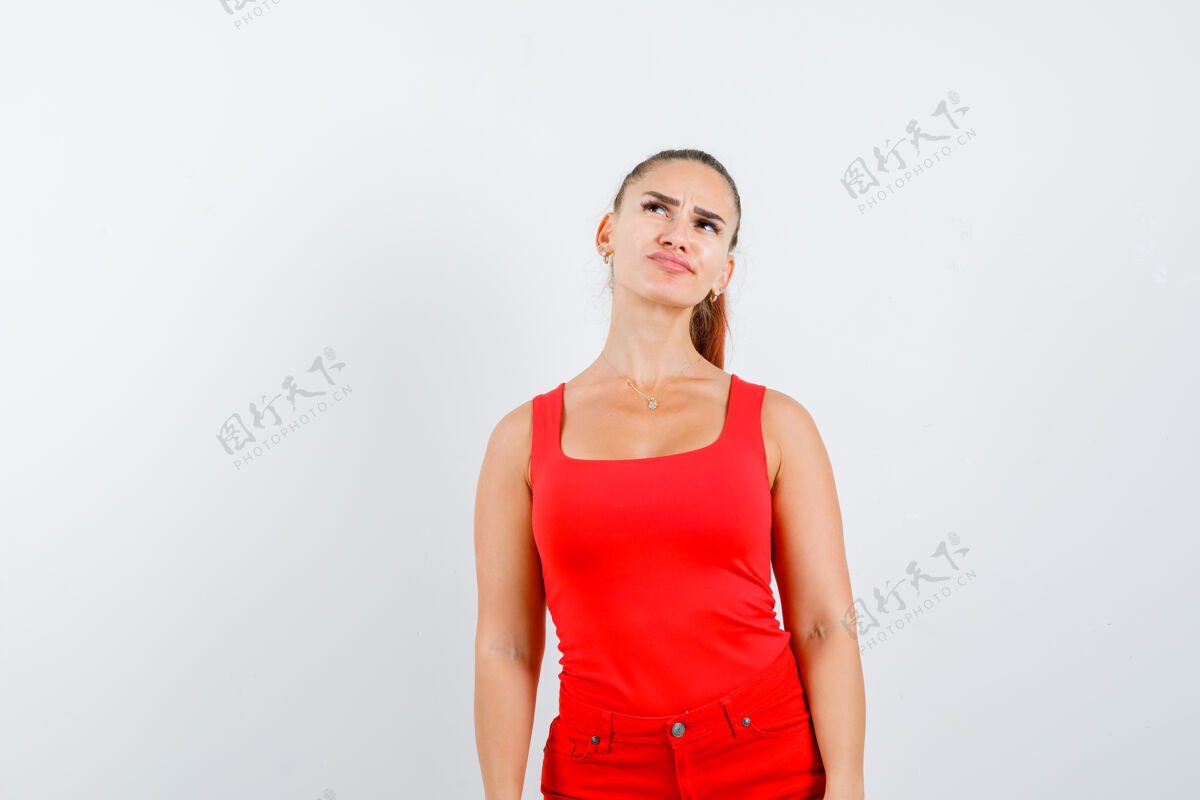 模特穿着红色单品 红色裤子的年轻女士一边摆姿势 一边看着一边沉思着 前面的景色护理年轻新鲜