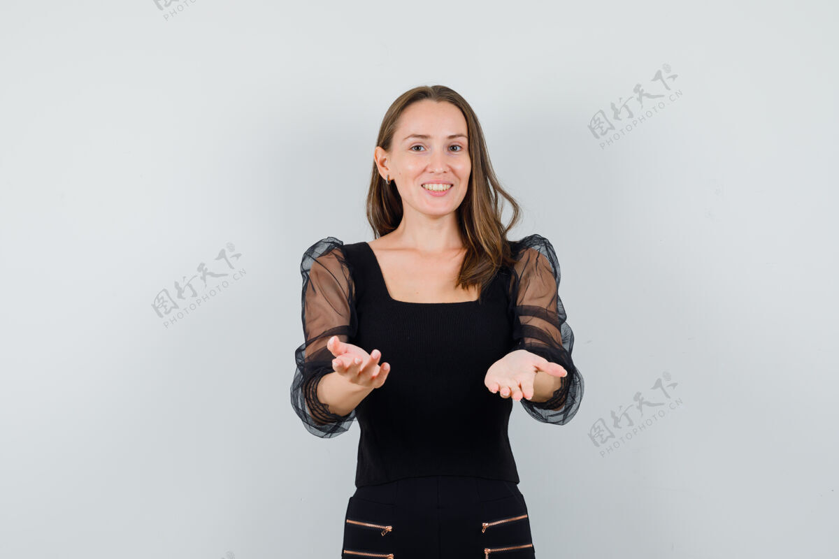 干净一个年轻的女人手牵着手 穿着黑色上衣和黑色裤子 看起来很高兴护理衬衫完美