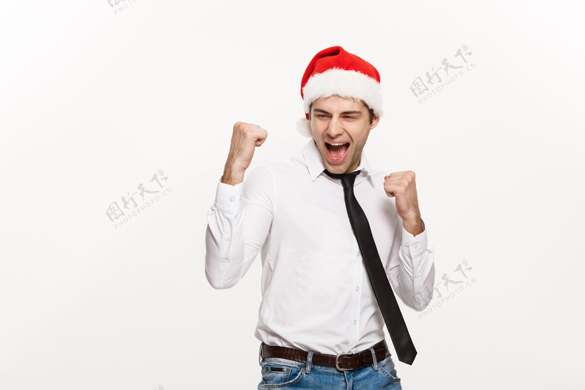男性帅气的商人戴着圣诞老人的帽子 在白色的脸上摆出令人惊讶的表情面部红色圣诞节