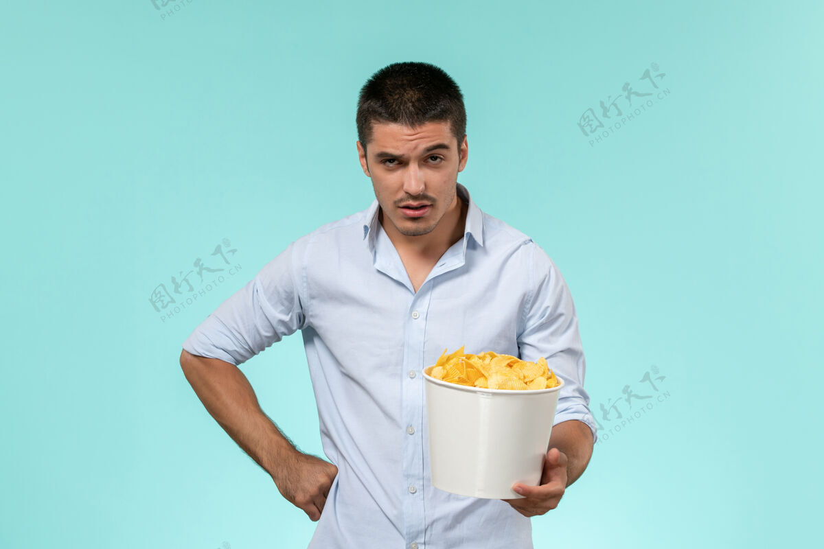 员工正面图：年轻的男性拿着蓝面薯片的篮子服务员剧院男