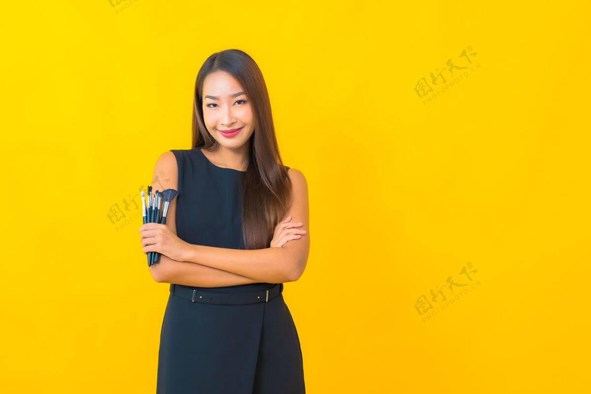 博客在黄色背景上用化妆刷描绘美丽的亚洲女商人流互联网亚洲人