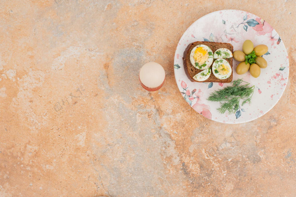 绿的烤面包加煮鸡蛋 橄榄放在白盘子里蛋黄盘子吐司